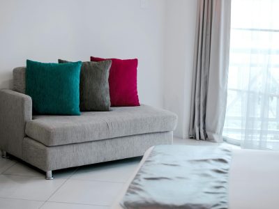 Simple modern interior featuring a grey sofa with vibrant colored cushions in a bright room.