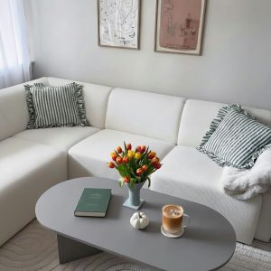 Elegant living room with pastel decor featuring a tulip bouquet and coffee on the table.