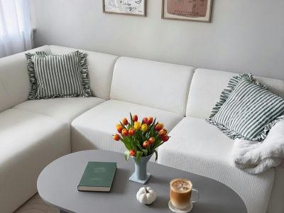 Elegant living room with pastel decor featuring a tulip bouquet and coffee on the table.