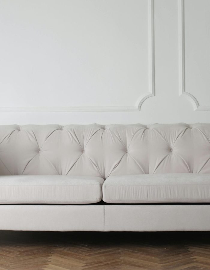 Luxurious white sofa in a modern minimalist interior with wooden flooring.