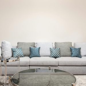 Modern room interior with decorative cushions on couch against round shaped tables on carpet at home